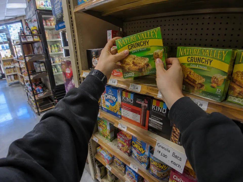 First-person view of hands placing boxed goods on a shop shelf.